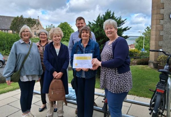Members of Dalmeny and Queensferry Church proudly display their Gold Award Certificate outside Queensferry Church, standing in front of the new bike rack – one of the many sustainable initiatives that contributed to the assessment.